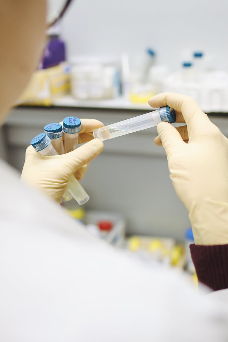 Scientist examining test tubes in a laboratory setting, wearing protective gloves.